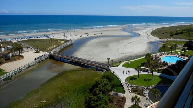 A beach resort with a swimming pool, a boardwalk, and a view of the ocean.