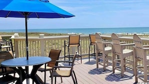 A deck with outdoor seating, a table, and a blue umbrella.