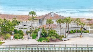 A beachfront property with a large house, a covered patio, and a view of the ocean.