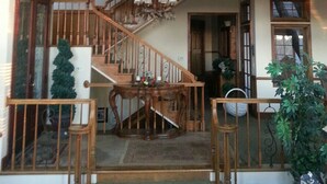 Ein geräumiges, mehrgeschossiges Interieur mit einer zentralen Treppe, Holzwertungen und einem Chandelier.