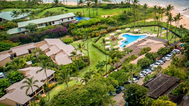 A resort with a swimming pool, beachfront, and lush greenery.