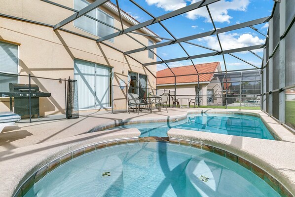 An indoor swimming pool with a glass ceiling, a barbecue area, and outdoor seating.