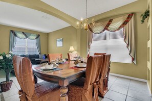A dining area with a wooden table, chairs, and a chandelier.