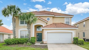 A two-story house with a red-tiled roof, a green door, and a garage. - Work & Play Here-Gated Resort Villa-5 Masters-Private Pool-Free Wifi-Near Disney (Davenport)