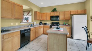 A kitchen with wooden cabinets, a microwave, a stove, a dishwasher, and a refrigerator. - Work & Play Here-Gated Resort Villa-5 Masters-Private Pool-Free Wifi-Near Disney (Davenport)