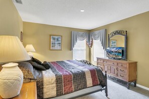 A bedroom with a bed, a dresser, a television, and a vase.