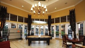 A pool table in a room with large windows, a chandelier, and a dining area with chairs. - Work & Play Here-Gated Resort Villa-5 Masters-Private Pool-Free Wifi-Near Disney (Davenport)