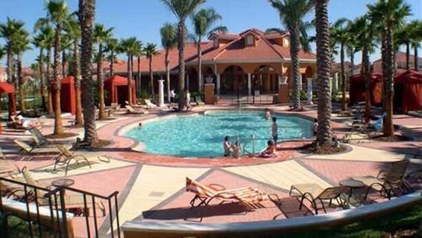 A resort pool area with palm trees, lounge chairs, and a building with a red roof. - Work & Play Here-Gated Resort Villa-5 Masters-Private Pool-Free Wifi-Near Disney (Davenport)