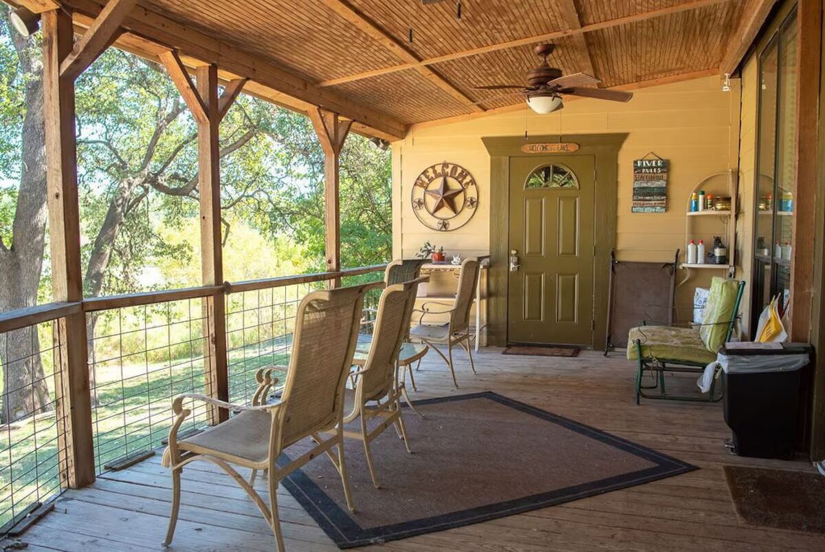 A covered porch with wooden chairs, a door labeled "Welcome," and a sign reading "River."