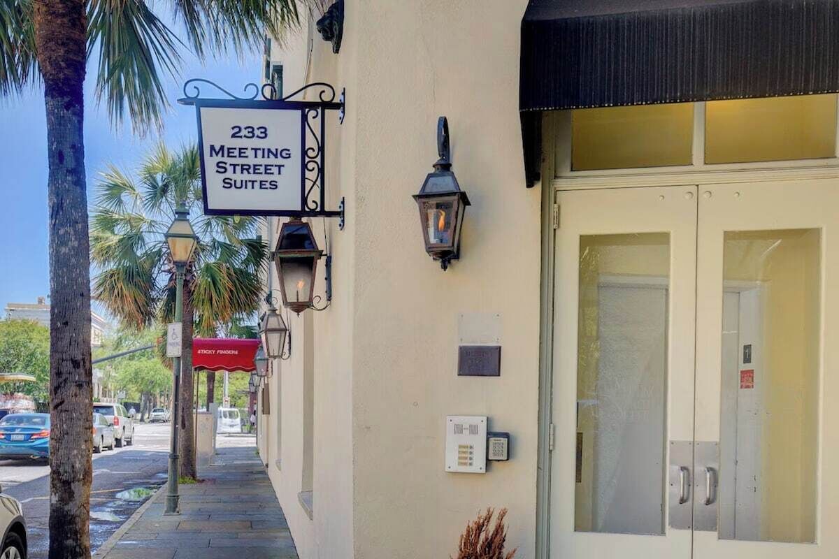 A hotel entrance with a sign for '233 Meeting Street Suites' and a red awning.