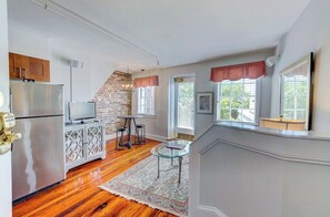 A kitchen with a refrigerator, a television, and a brick wall.