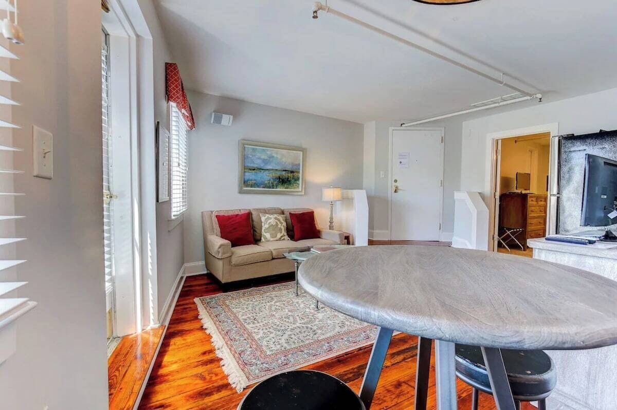 A room with a sofa, a table, a rug, and a painting on the wall.