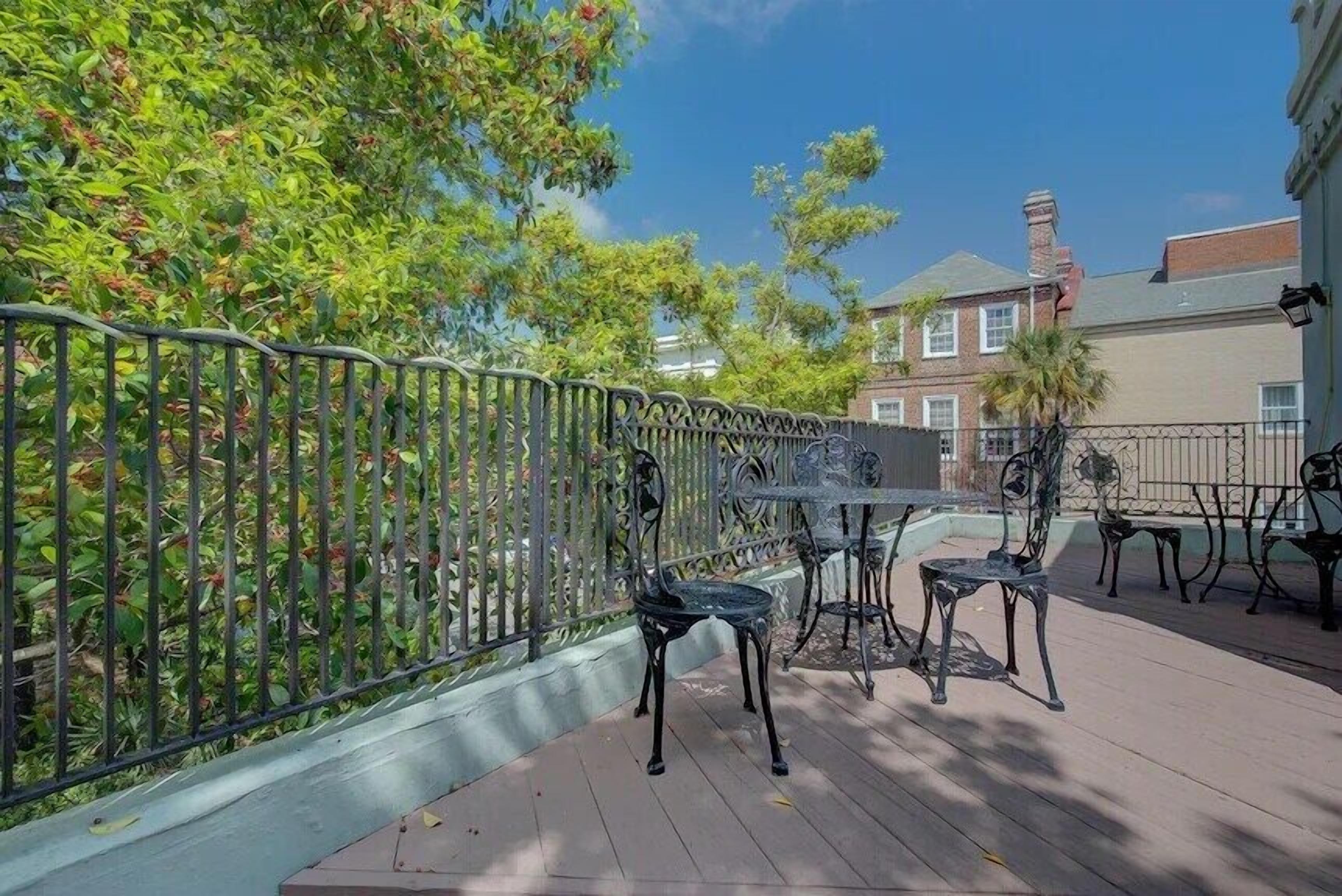 An outdoor patio with a metal fence, outdoor seating, and a building in the background.