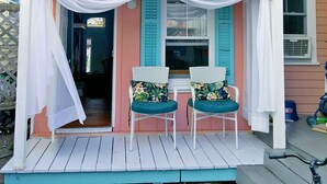 A porch with two wicker chairs, a small covered area with white drapes, and a window with blue shutters. - The Cupcake Guest House, historic Ocean Grove. 2-blocks to beach, whole house 4U (Ocean Grove)