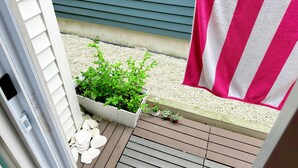 A balcony with a hanging pink and white striped towel, a potted plant, and a small white planter with shells. - The Cupcake Guest House, historic Ocean Grove. 2-blocks to beach, whole house 4U (Ocean Grove)