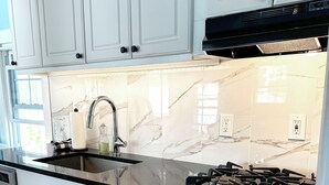 A modern kitchen with white cabinets, a black countertop, and a gas stove. - The Cupcake Guest House, historic Ocean Grove. 2-blocks to beach, whole house 4U (Ocean Grove)
