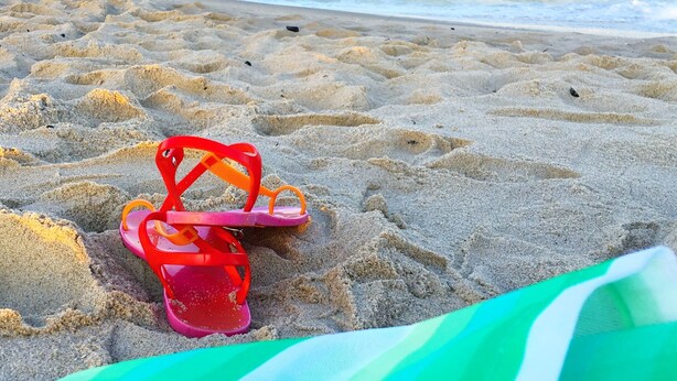 A beach with a pair of red flip-flops and a green towel on the sand. - The Cupcake Guest House, historic Ocean Grove. 2-blocks to beach, whole house 4U (Ocean Grove)