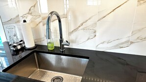 A kitchen sink with a modern faucet, a soap dispenser, and a glass container on the countertop. - The Cupcake Guest House, historic Ocean Grove. 2-blocks to beach, whole house 4U (Ocean Grove)