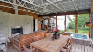 A covered outdoor area with a wooden table, benches, a hot tub, and a fireplace. - Warren Dunes - Large 2 Br-2 Bath, Hot Tub, Wbfpl , Next To Wineries (Bridgman)