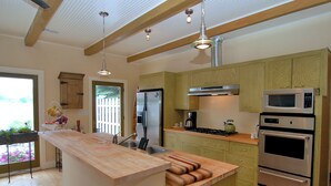 A modern kitchen with wooden cabinets, stainless steel appliances, and a wooden island with a built-in sink. - Warren Dunes - Large 2 Br-2 Bath, Hot Tub, Wbfpl , Next To Wineries (Bridgman)