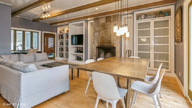 A modern living room with a large wooden dining table, white chairs, a grey sofa, and a fireplace. - Warren Dunes - Large 2 Br-2 Bath, Hot Tub, Wbfpl , Next To Wineries (Bridgman)