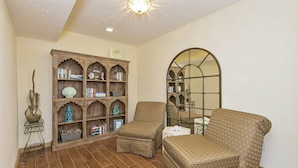 A living room with a patterned sofa, a wooden bookshelf, and a decorative mirror.
