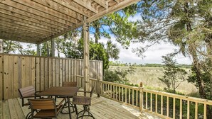 A wooden deck with a table and chairs, surrounded by a wooden railing and trees.