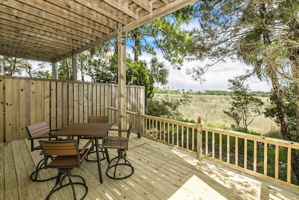 A wooden deck with a table and chairs, surrounded by a wooden railing and trees.
