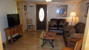 A living room with a television, a sofa, a coffee table, and a door with a decorative glass panel.
