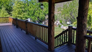 A wooden deck with a railing overlooking a landscaped garden with a pond and rocks. - Luxury Log Home Retreat near Zion National Park (Toquerville)