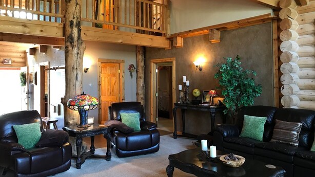 A log cabin interior with a loft bedroom, leather furniture, and a rustic decor. - Luxury Log Home Retreat near Zion National Park (Toquerville)