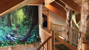 A wooden staircase with a view of a forest mural, wooden railings, and a wooden floor with patterned rugs. - Luxury Log Home Retreat near Zion National Park (Toquerville)