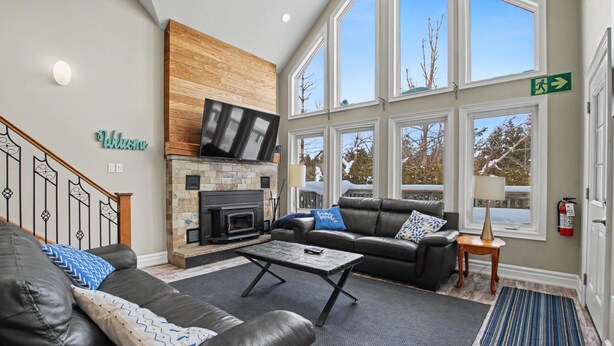 A modern living room with a fireplace, leather sofas, and large windows. - Executive Blue Mountain Chalet, 6 Bedrooms, Sauna (Blue Mountains)