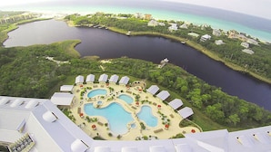 Vista aérea de un resort con varias piscinas, un puerto deportivo y abundante vegetación.