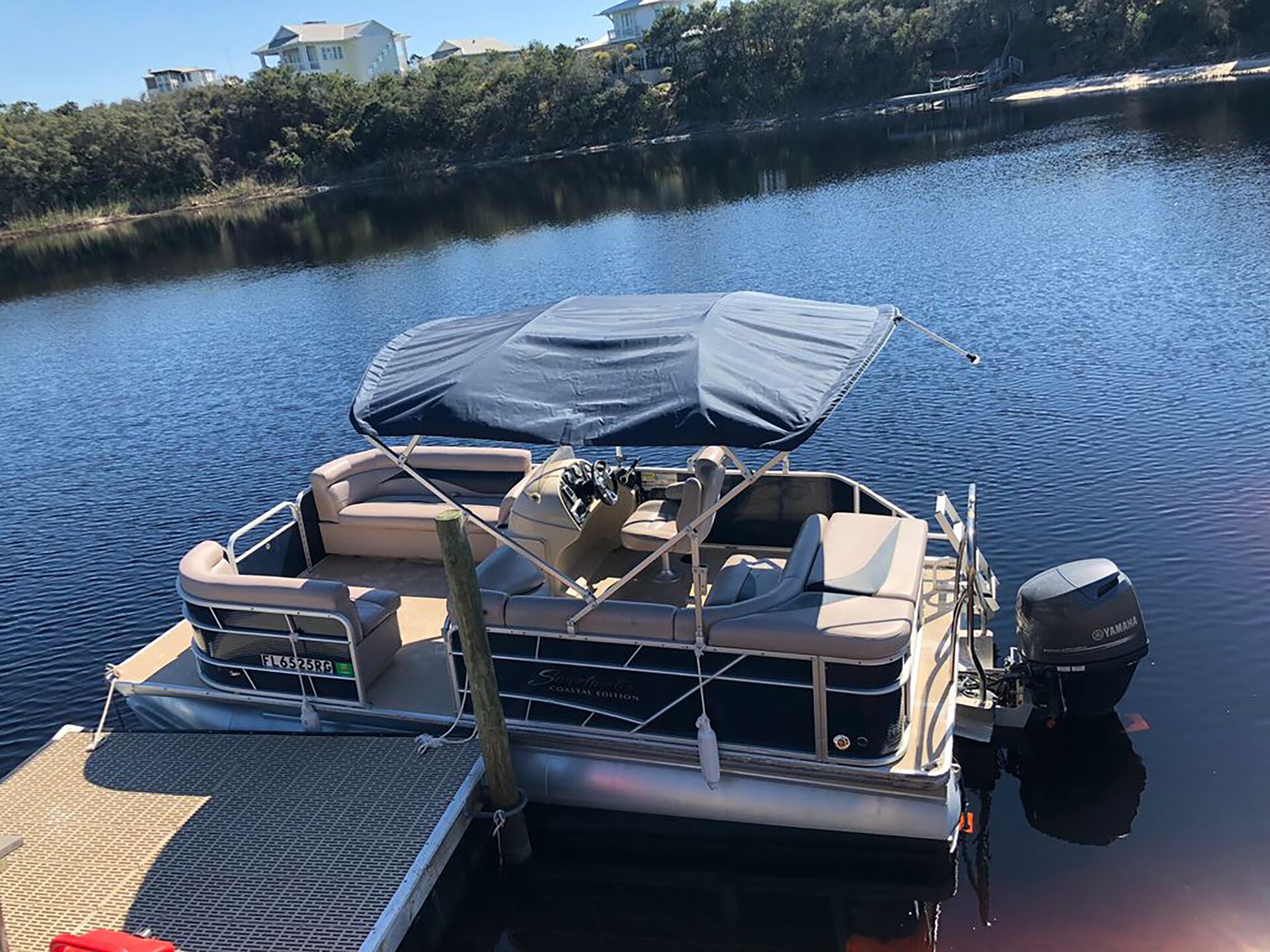 Un barco amarrado en el muelle con una zona de estar techada, un motor fueraborda Yamaha y un número de registro visible.