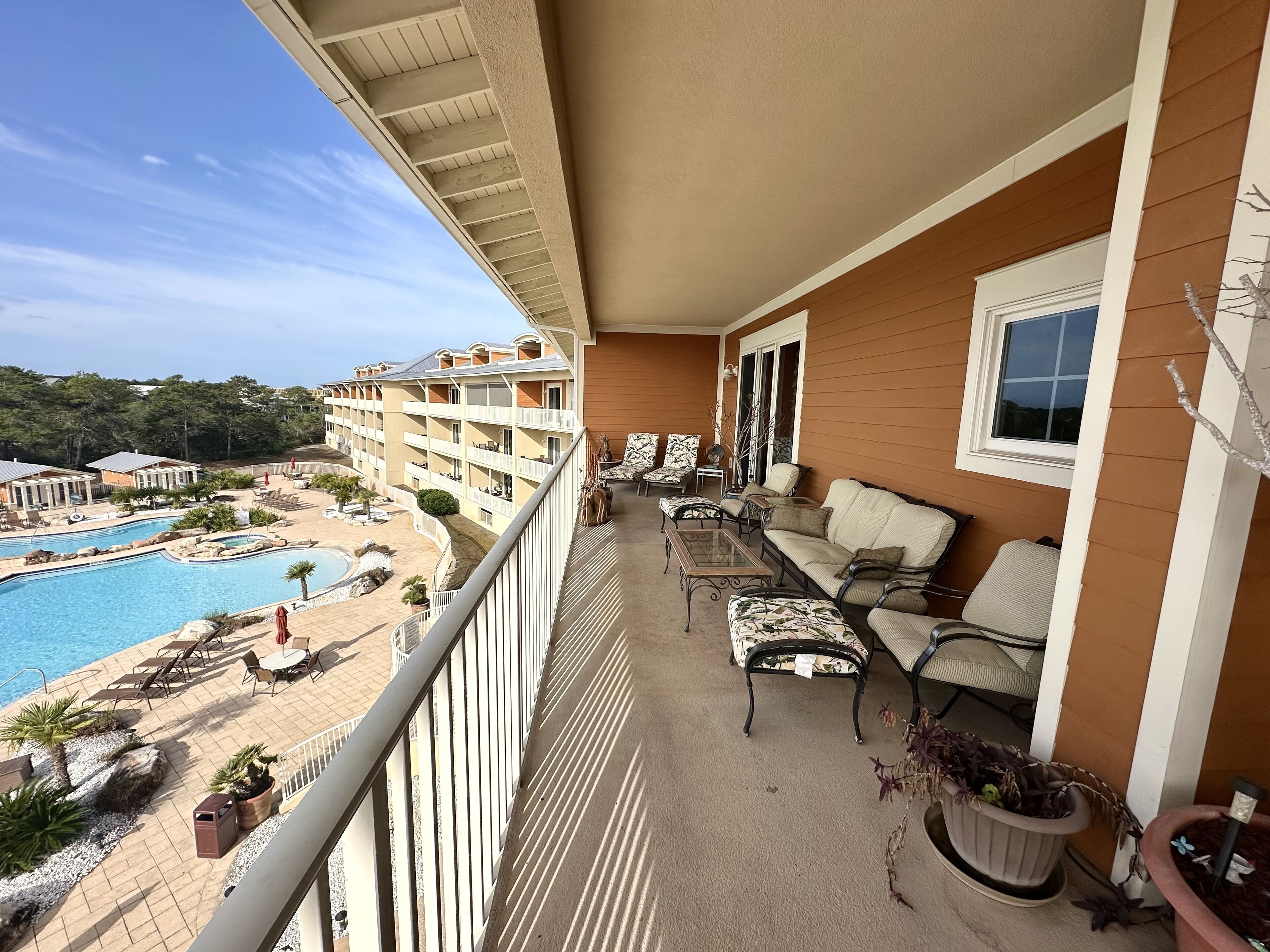 En balkon med udendørs møbler, en pool og udsigt til en resortbygning.
