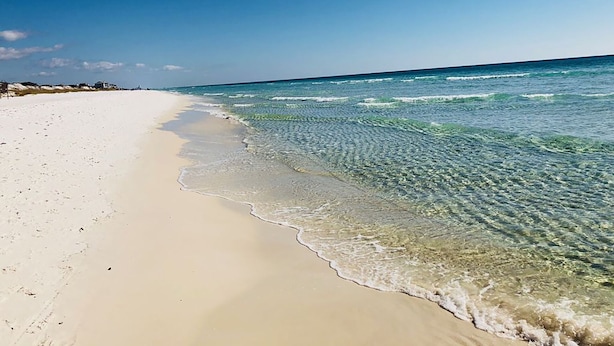 Una playa con aguas cristalinas y poca profundidad, y una orilla arenosa.