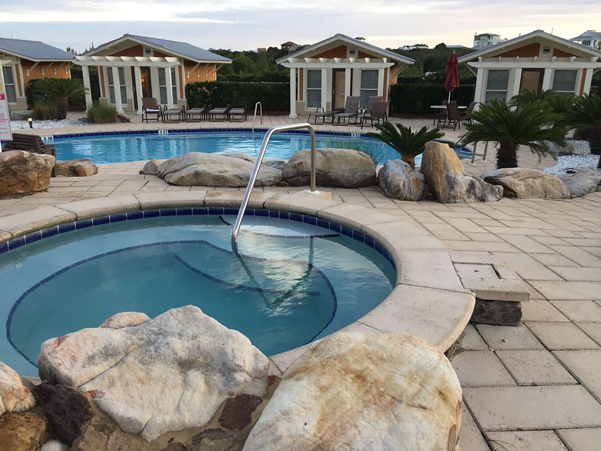 A swimming pool with a circular design, surrounded by large rocks and a tiled deck.