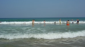 Una platja amb gent a l'aigua i a la riba.