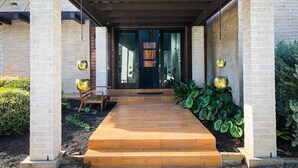 A covered entrance with a wooden walkway leading to a glass door. - Modern Austin Retreat Getaway - exquisite home! (Round Rock)