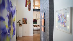 A hallway with art installations, a brick wall, and a wooden floor. - Modern Austin Retreat Getaway - exquisite home! (Round Rock)