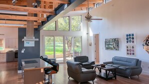 A spacious living area with a high ceiling, large windows, and a modern kitchen in the background. - Modern Austin Retreat Getaway - exquisite home! (Round Rock)