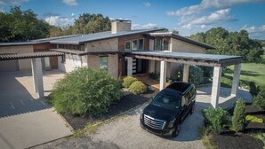A modern two-story house with a covered driveway and a black SUV parked in the driveway. - Modern Austin Retreat Getaway - exquisite home! (Round Rock)