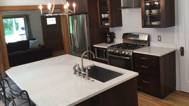 Una cocina moderna con una isla central, electrodomésticos de acero inoxidable y armarios de madera oscura.