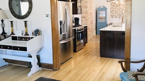 Una cocina moderna con electrodomésticos de acero inoxidable, una mesa de comedor de madera y una silla azul.