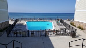 Ein Pool mit Blick auf den Ozean, umgeben von Liegestühlen und einem Zaun.