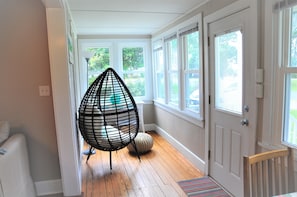 A hallway with a wooden floor, a white door, and a black hanging chair. - 200 steps to the beach! (Rock Hall)