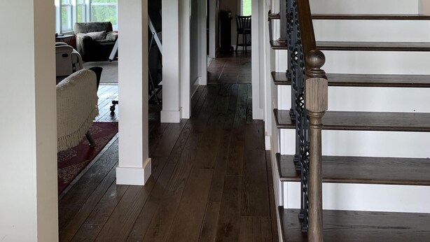 A spacious interior with a wooden staircase, a living area with a sofa and a television, and a framed picture on the wall. - Breathtaking Country Paradise with hot tub  where you can unplug in nature  (Beechgrove)