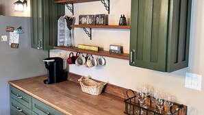 A kitchen with green cabinets, wooden countertops, and various kitchen items. - Breathtaking Country Paradise with hot tub  where you can unplug in nature  (Beechgrove)