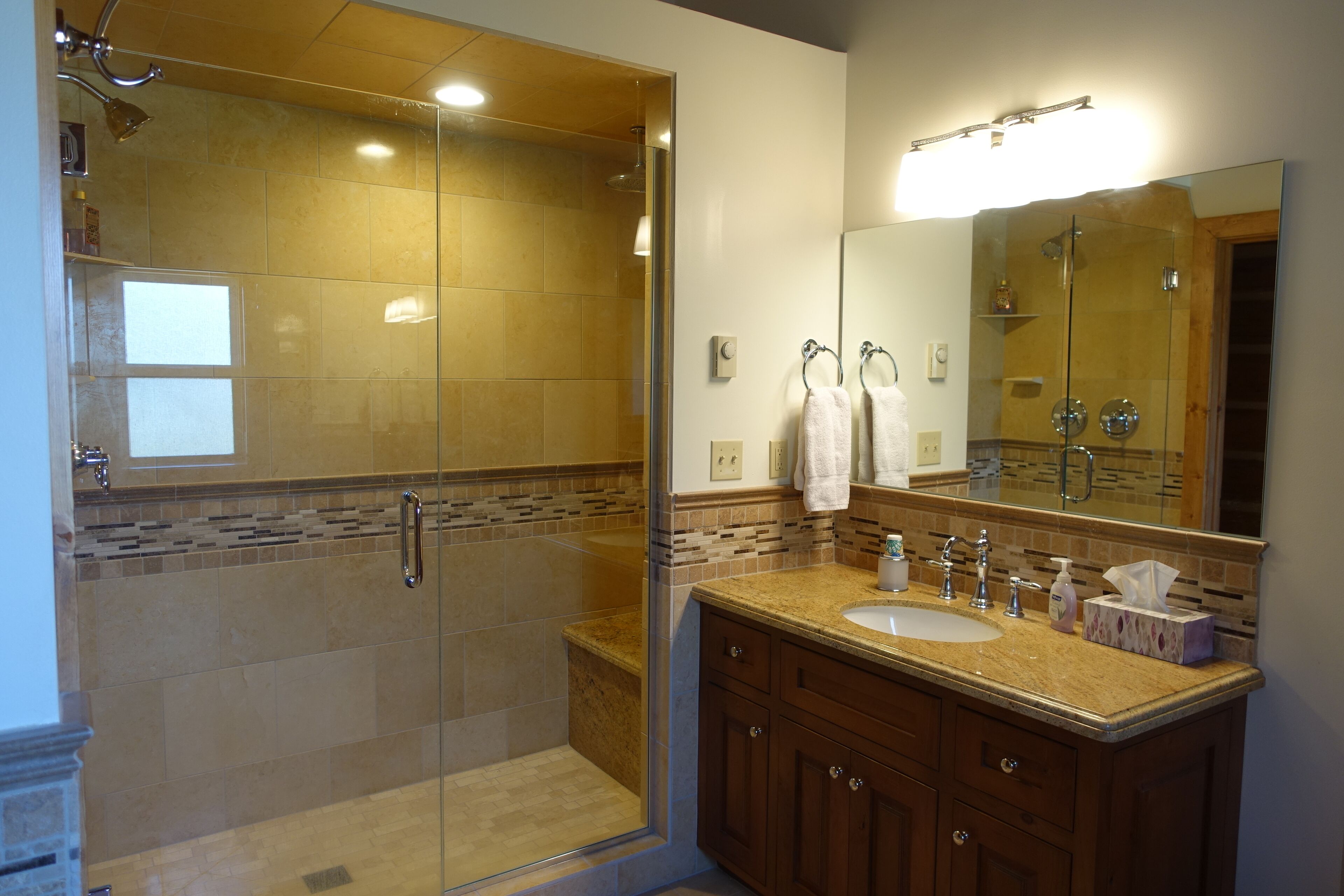 Une salle de bain moderne avec une douche à parois de verre, un grand miroir et des meubles en bois.